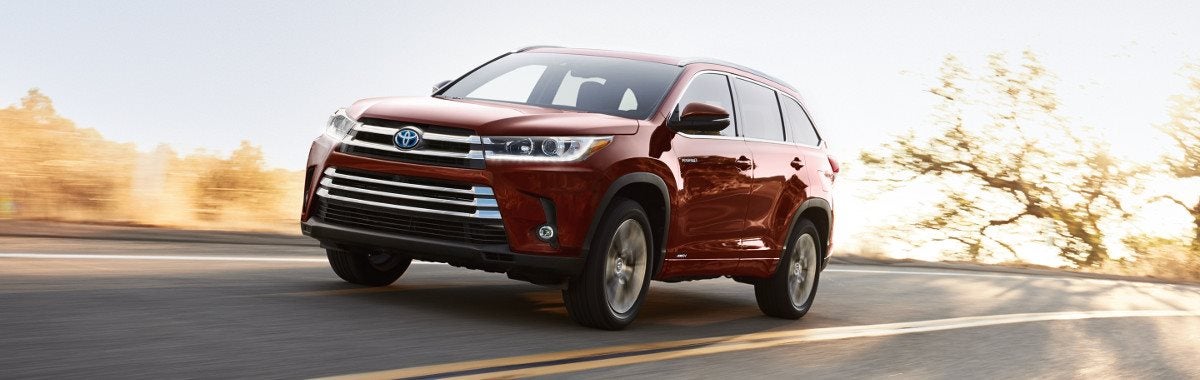 A red 2019 Toyota Highlander driving down an open road