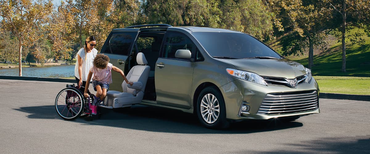 Woman helping her daughter from her wheel chair to the Auto Access Seat on the 2020 Toyota Sienna