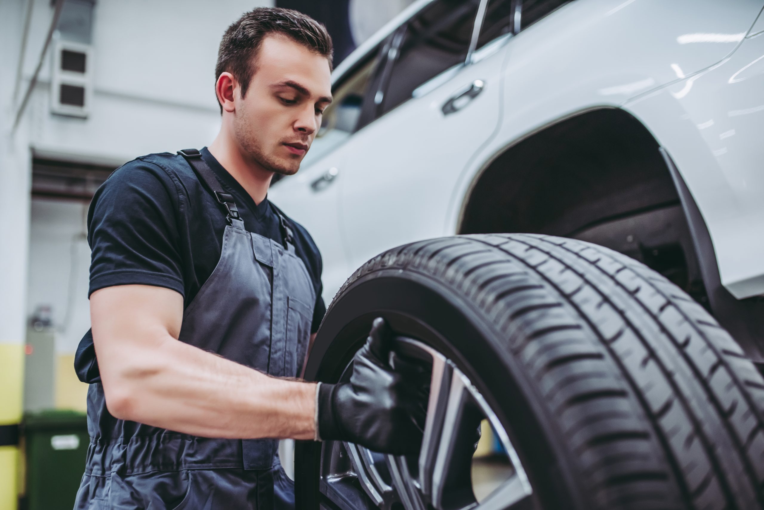 A mechanic inspects a tire while working on a vehicle in a garage.