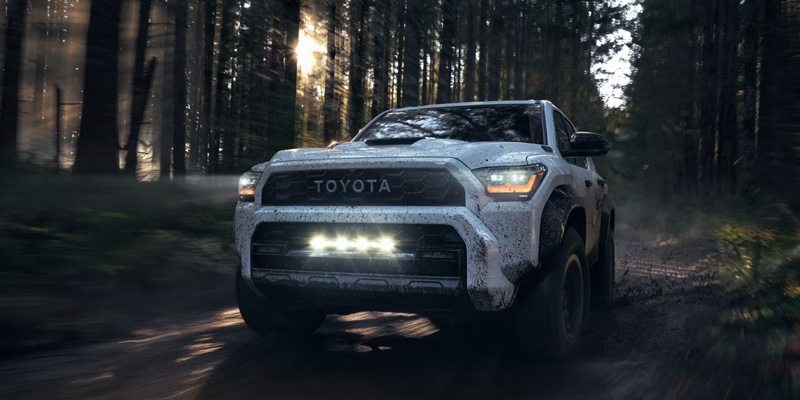 A Toyota 4Runner navigating through a dense forest, showcasing its off-road capabilities amidst tall trees.