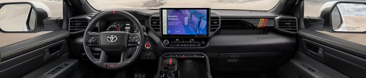 2026 Toyota Tundra in St. Louis, MO infotainment system displaying navigation, trailering apps, and media control while driving through downtown or suburban areas.