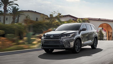 A silver 2019 Toyota Highlander driving down a suburban road