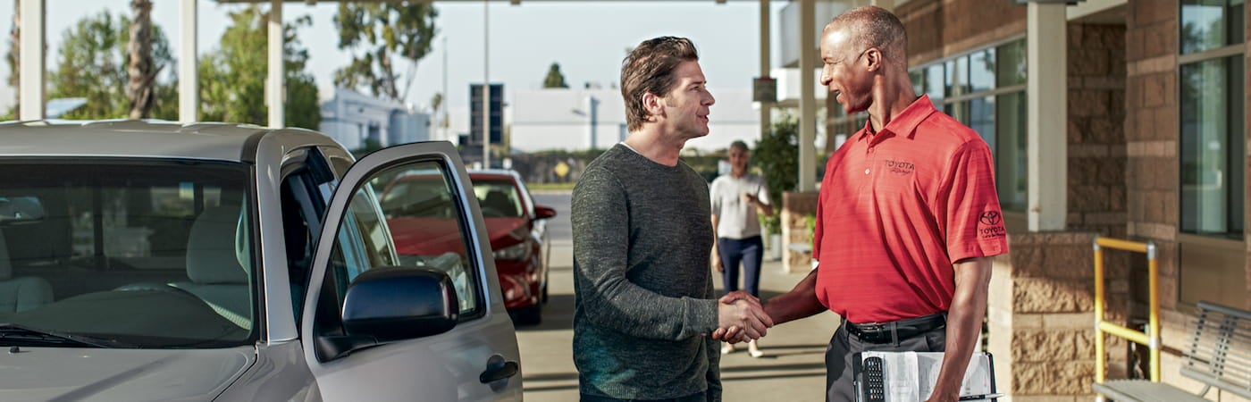 A man and a Toyota service technician shaking hands at a dealership