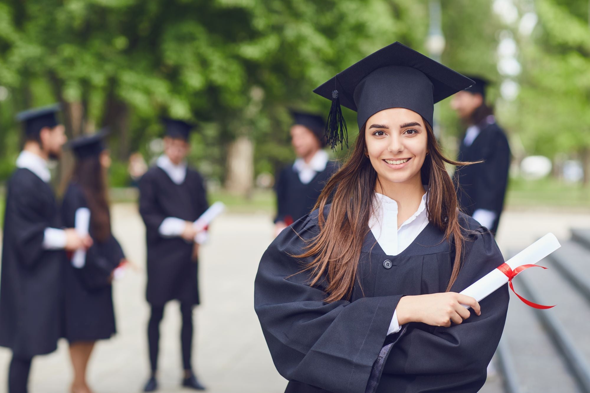 A woman in a graduation gown proudly holds her diploma
