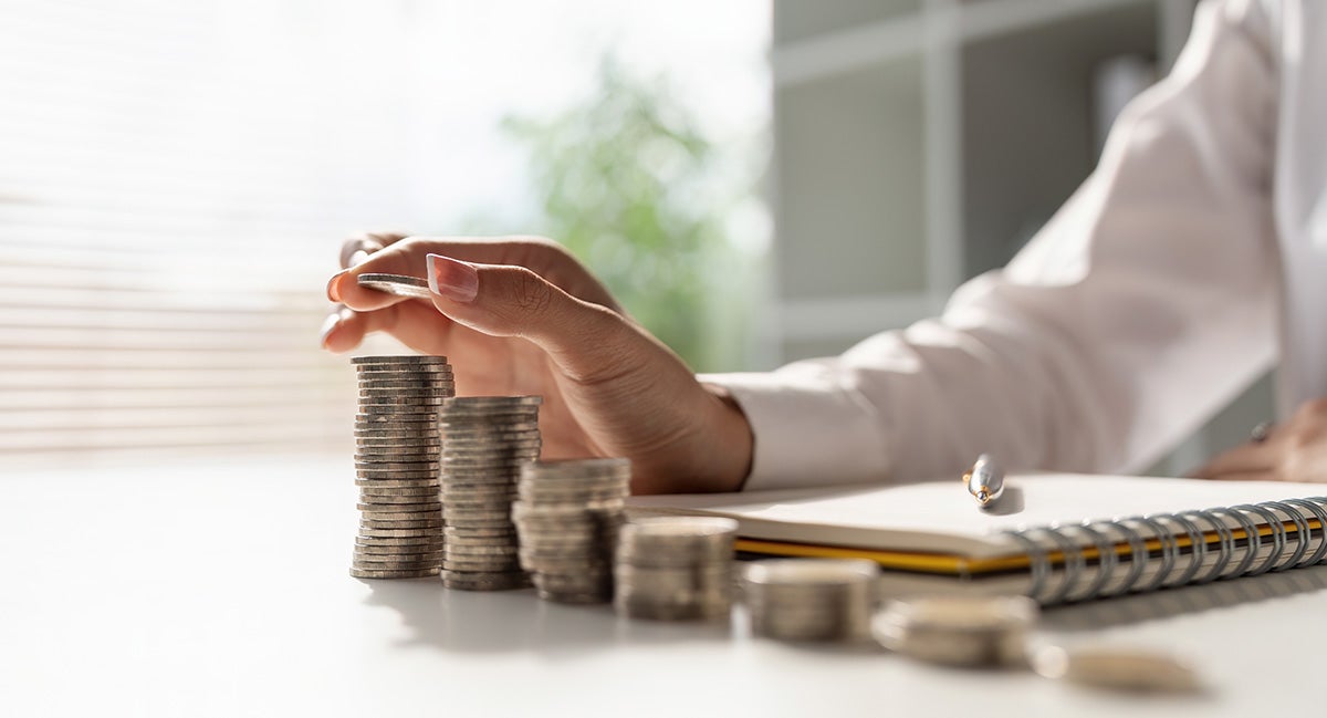 A man at a desk is stacking quarters sitting above his auto financing pen and notebook.